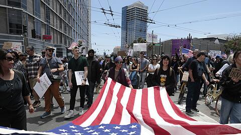 Demonstranten in San Francisco marschierten mit einer großen US-Flagge.