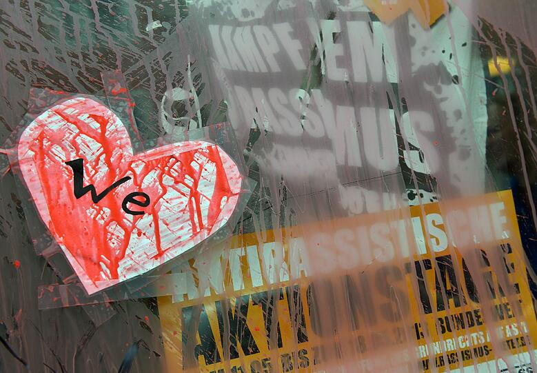 Ein mit roter Farbe beschmiertes Papierherz mit der Aufschrift "We" klebt an der Eingangstür eines mit Farbe verunstalteten Hauses im Münchner Stadtteil Westend.