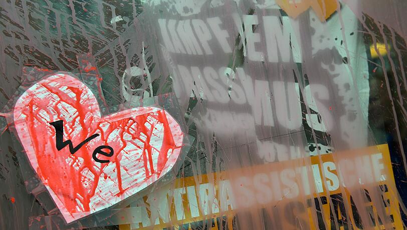 Ein mit roter Farbe beschmiertes Papierherz mit der Aufschrift "We" klebt an der Eingangstür eines mit Farbe verunstalteten Hauses im Münchner Stadtteil Westend.