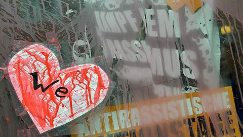 Ein mit roter Farbe beschmiertes Papierherz mit der Aufschrift "We" klebt an der Eingangstür eines mit Farbe verunstalteten Hauses im Münchner Stadtteil Westend.