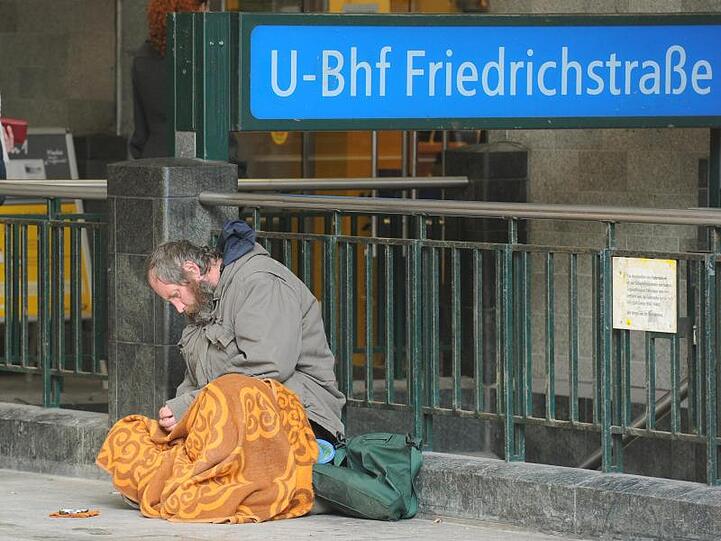 Ein obdachloser Mann sitzt am Berliner U-Bahnhof Friedrichstraße - übernachten darf er dort auch bei strenger Kälte nicht.