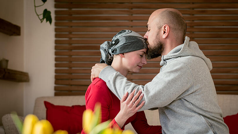 Ein Mann küsst seine krebskranke Frau. Emotionale Unterstützung ist für Betroffene jetzt besonders wichtig, sagt Onkologe Wolff.