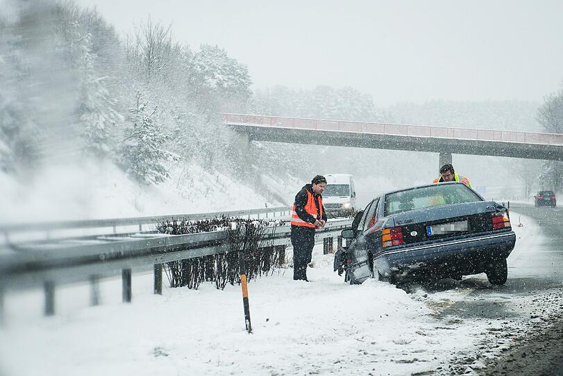 Ein Pkw steht auf der A70 bei Schirradorf (Bayern) nach einem Unfall auf schneebedeckter Fahrbahn an der Leitplanke.