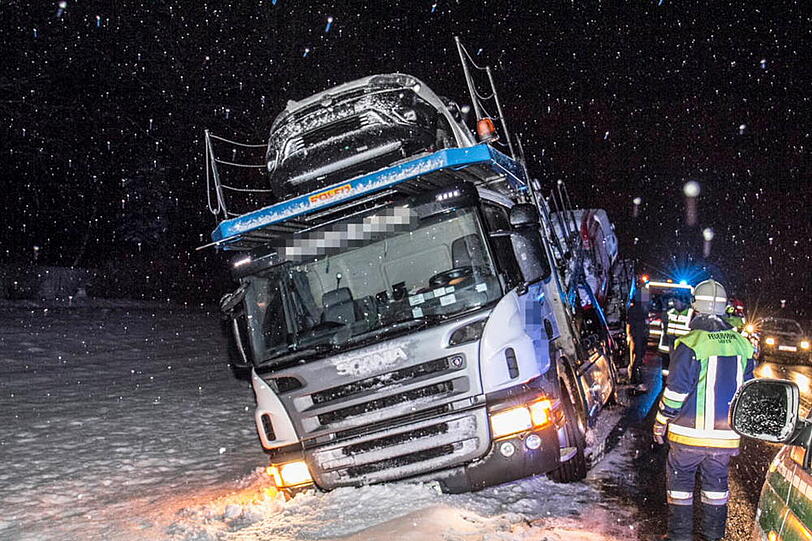Ein Autotransporter rutscht aufgrund der schneeglatten Fahrbahn in den Graben