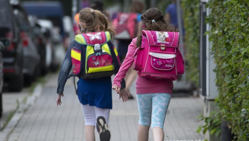 Zwei Schülerinnen einer Grundschule rennen mit einem Schulranzen auf dem Rücken die letzten Meter bis zum Schulhof. Zwei Schülerinnen einer Grundschule rennen mit einem Schulranzen auf dem Rücken die letzten Meter bis zum Schulhof.