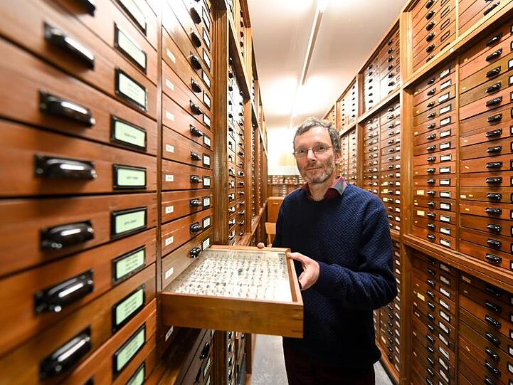 Stefan Schmidt, Insektenforscher an der Zoologischen Staatssammlung, mit einem Kasten mit präparierten Insekten. Foto: Tobias Hase/Archiv