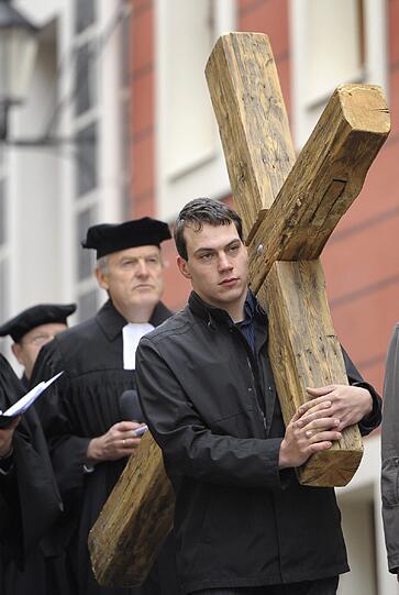 Junge Männer tragen am Freitag (06.04.12) ein hölzernes Kreuz an der Spitze einer Kreuzweg-Prozession. Etwa 500 Christen gehen symbolisch zur Sterbestunde Christi in Görlitz von der St. Peter und Paul-Kirche durch die Stadt zur Kapelle beim Heiligen Grab.