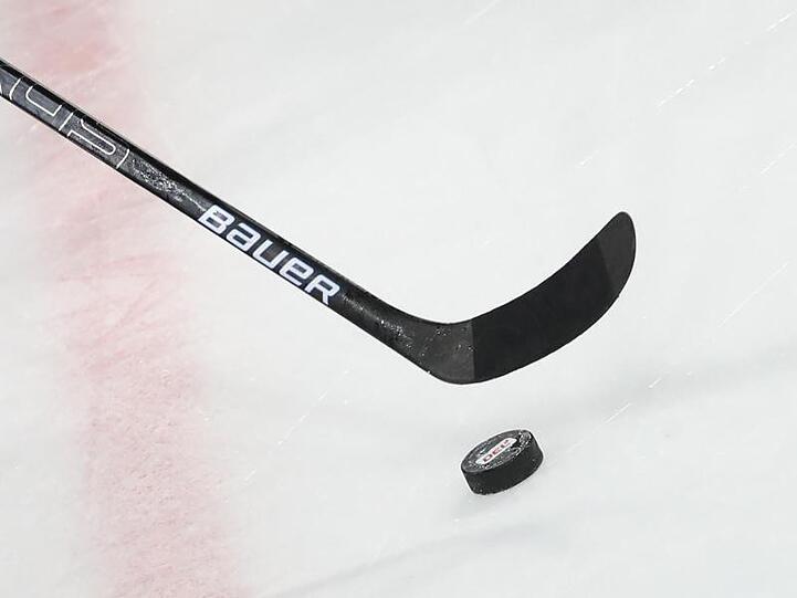 Ein Puck liegt vor einem Schläger im Spiel auf dem Eis. Foto: Daniel Karmann/dpa/Symbolbild