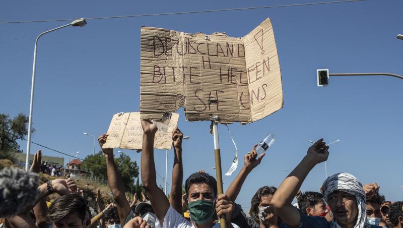 Ein Flüchtling auf Lesbos hält ein Plakat mit der Aufschrift "Deutschland, bitte helfen sie uns". FGriechenland helfen").