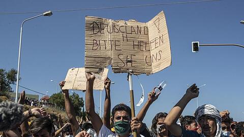 Ein Flüchtling auf Lesbos hält ein Plakat mit der Aufschrift "Deutschland, bitte helfen sie uns". FGriechenland helfen").