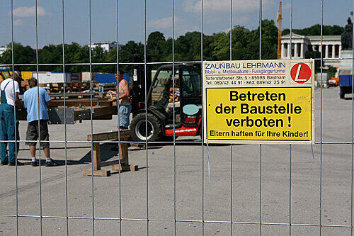 Mehrere Bauarbeiter arbeiten am Mittwoch (16.07.2008) hinter einem Absperrzaun auf der Theresienwiese.