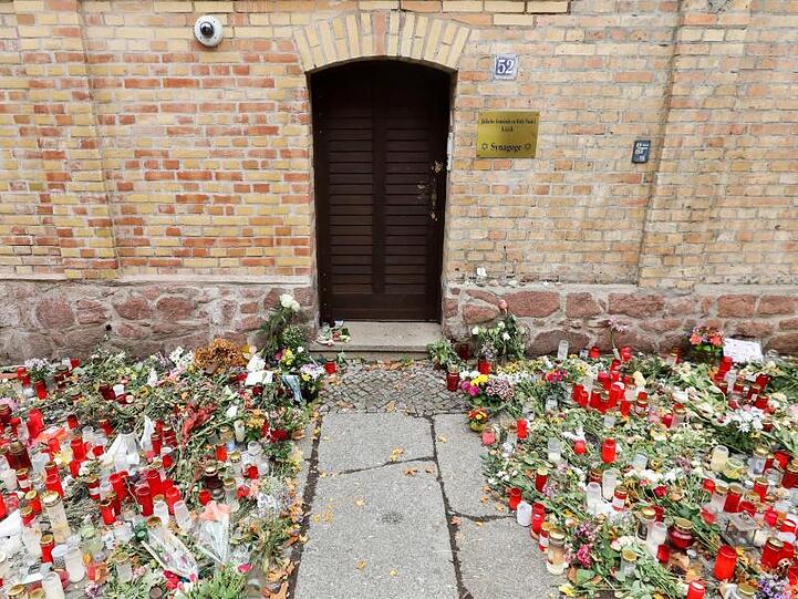 Nur noch ein schmaler Weg führt zwischen den Blumen und Kerzen zur Tür der Synagoge Halle.