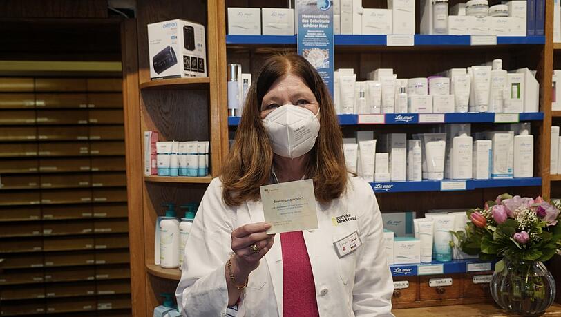 Apothekerin Elisabeth Huber mit einem "Berechtigungsschein" der Krankenkasse, auf den es die neuen Masken für Ältere (fast) kostenlos gibt. Apothekerin Elisabeth Huber mit einem "Berechtigungsschein" der Krankenkasse, auf den es die neuen Masken für Ältere (fast) kostenlos gibt.