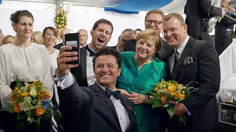 Der Tenor Piotr Beczala - 2018 als Lohengrin bei den Bayreuther Festspielen - macht beim Staatsempfang nach der Premiere ein Selfie mit der Kanzlerin. Links seine Kollegin Anja Harteros.