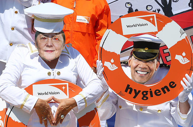 Demonstranten mit den Masken von Angela Merkel und Barack Obama.