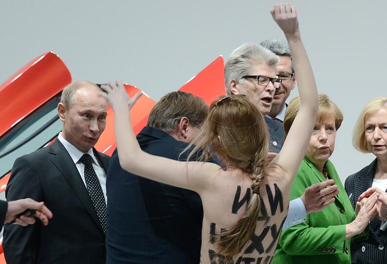Die Aktivistinnen hatten auf ihren entblößten Oberkörpern große Schriftzüge, die Putin als Dikatatoren bezeichneten. Sie schafften es nahe an die Bundeskanzlerin und den russischen Präsidenten heran, bis die Sicherheitskräfte eingreifen konnten.
