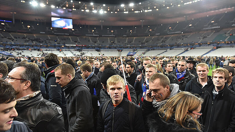 Menschen stehen nach dem Spiel auf dem Rasen des Stade de France. Teilweise war das Mobilfunknetz unterbrochen. Menschen stehen nach dem Spiel auf dem Rasen des Stade de France. Teilweise war das Mobilfunknetz unterbrochen.