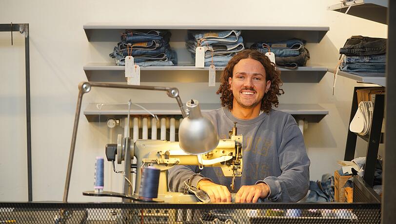 Manuel Egner an der Industrienähmaschine im Nudie Jeans Repair Shop an der Rumfordstraße 2 in München. Hier repariert er Jeans für die Kundinnen und Kunden kostenlos. Manuel Egner an der Industrienähmaschine im Nudie Jeans Repair Shop an der Rumfordstraße 2 in München. Hier repariert er Jeans für die Kundinnen und Kunden kostenlos.