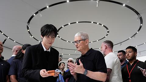 2026: Apple Chef Tim Cook (M) steht unter Druck, ein neues gro&szlig;es Ding - "One More Thing" abzuliefern.