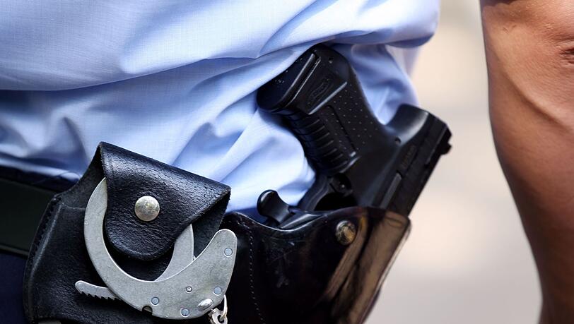 Ein Polizist trägt Handschellen und seine Dienstwaffe bei sich.