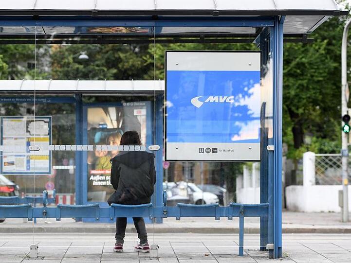 Eine Frau wartet an einer Straßenbahnhaltestelle. Foto: Tobias Hase/Archivbild
