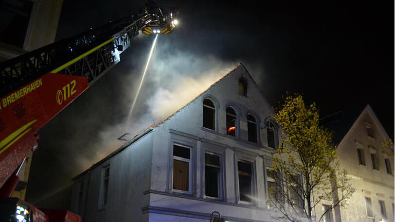 Feuerwehrmänner löschen den Brand in einem Mehrfamilienhaus in Bremerhaven.