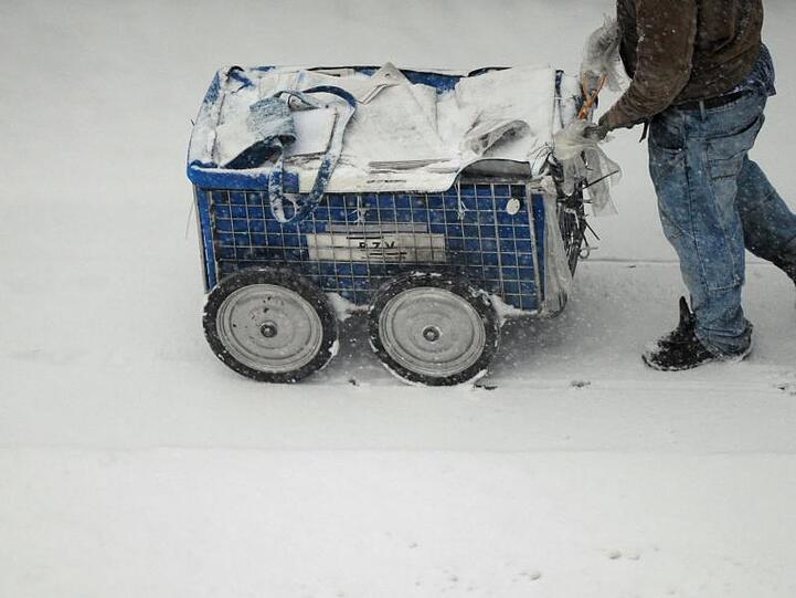 Arbeiten zum Mindestlohn: Ein Zeitungszusteller ist am frühen Morgen bei dichtem Schneetreiben in Berlin unterwegs.