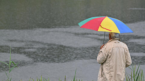 Ein Mann mir Regenschirm steht am Fluss Schwarze Elster. Heute gibt es im S&uuml;den und Osten dichte Wolken und bis in die Mitte sowie in den Nordosten ausgreifenden Regen. Lokal kann es zu Gewittern kommen. Die Temperaturen steigen laut Deutschem Wetterdienst auf 17 bis 21 Grad. +++ dpa-Bildfunk +++