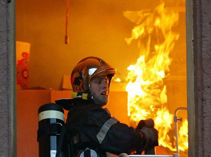 Ein Feuerwehrmann am Fenster eines brennenden Hauses (Symbolbild)