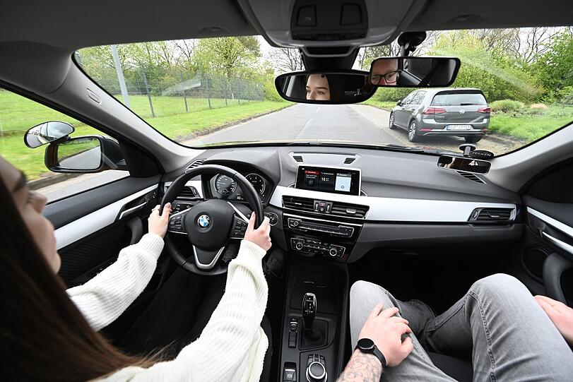 Eine Fahrschülerin sitzt am Steuer, daneben ihr Fahrlehrer.