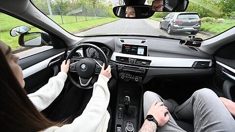 Eine Fahrschülerin sitzt am Steuer, daneben ihr Fahrlehrer.