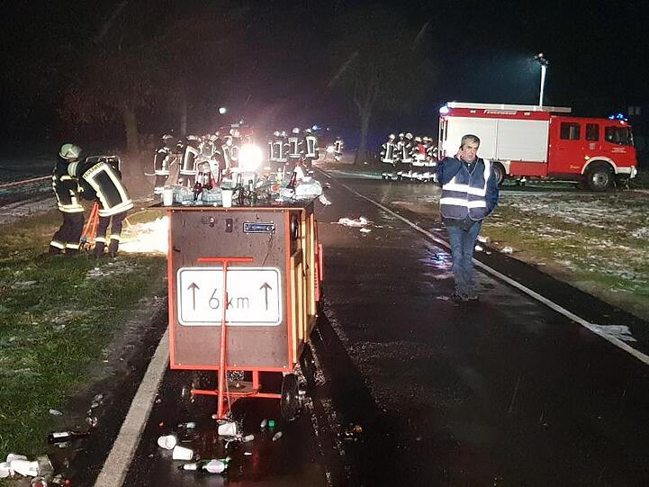 Einsatzkräfte der Feuerwehr stehen auf einer Landstraße nahe Breddenberg im Landkreis Emsland an der abgesperrten Unfallstelle.