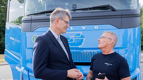 Lkw-Fahrerinnen und Lkw-Fahrer sollen laut Minister Schnieder (links) profitieren.