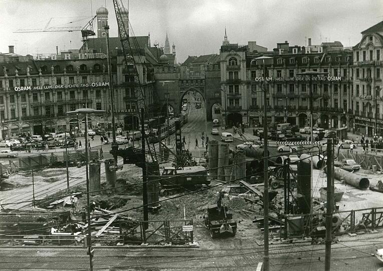 Anno 1964: Im Zuge des S- und U-Bahnbaus wird der Stachus zur Großbaustelle. In den folgenden Jahren werden immer wieder andere Wege über den Karlsplatz führen. 1972 wird dann endlich die U-Bahnstation eröffnet.