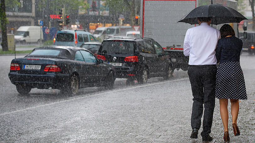 Passanten laufen in München durch einen Hagelschauer. Foto: Florian Eckl
