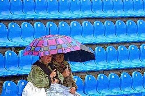 Tristesse am Center Court: Zwei Zuschauer kauern unter einem Regenschirm. Und die weiteren Aussichten? Nicht wirklich gut.