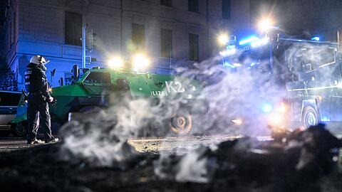 Polizisten stehen hinter einer rauchenden Barrikade im Stadtteil Connewitz in Leipzig.