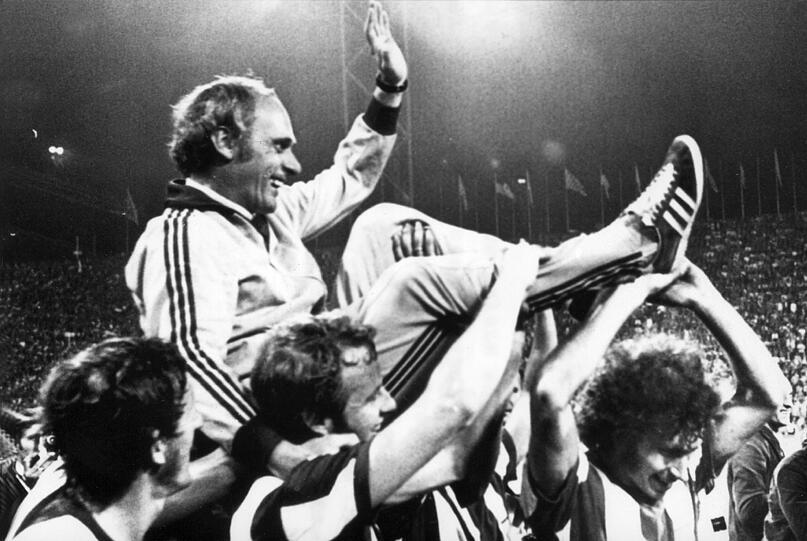 Jubelnd tragen die Bayern-Spieler mit Paul Breitner (r, unten) ihren Trainer Udo Lattek (oben) am 28.6.1972 auf einer Ehrenrunde durch das mit fast 80.000 Zuschauern ausverkaufte Münchner Olympiastadion.