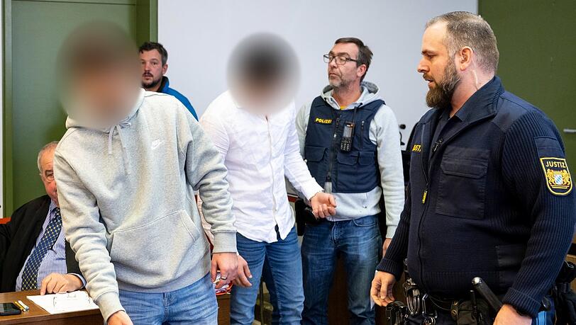 Zwei Angeklagte werden von Justizbeamten zum Prozess in den Gerichtssaal des Landgerichts München gebracht.