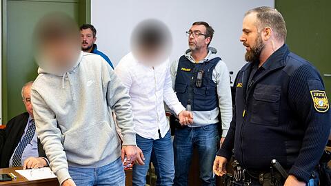 Zwei Angeklagte werden von Justizbeamten zum Prozess in den Gerichtssaal des Landgerichts München gebracht.
