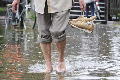 Eine Frau traegt am Samstag (07.08.10) in Starnberg (Bayern) ihre Schuhe, waehrend sie barfuss durch das Wasser läuft.