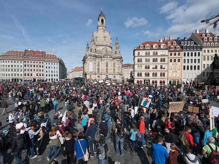Demonstranten stehen in Dresden mit Schildern und Transparenten auf dem Neumarkt vor der Frauenkirche.