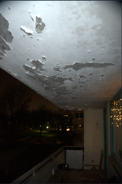 Der Putz blättert von der Decke eines Balkons ab.