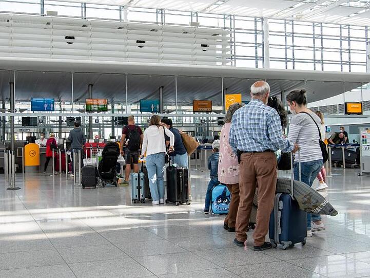 Fluggäste warten im fast leeren Terminal 2 des Münchener Flughafens auf den Check-In.