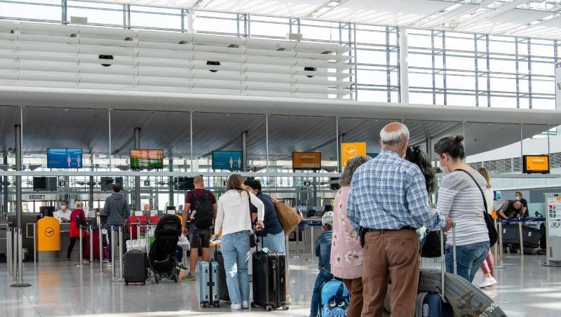 Fluggäste warten im fast leeren Terminal 2 des Münchener Flughafens auf den Check-In. Fluggäste warten im fast leeren Terminal 2 des Münchener Flughafens auf den Check-In.