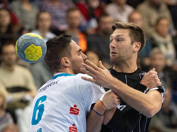 Harald Reinkind (r) vom THW Kiel wird von TVB-Spieler Dominik Weiß gebremst.
