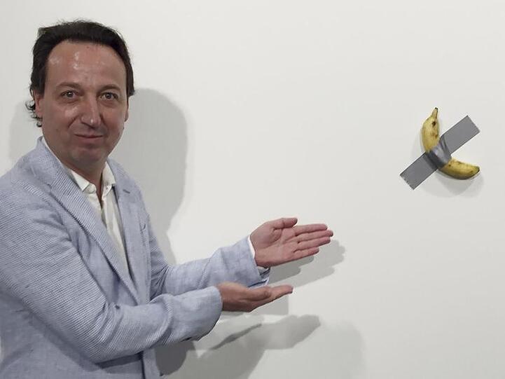 Galerist Emmanuel Perrotin zeigt auf das Kunstwerk "Comedian" von Maurizio Cattelan auf der Art Basel in Miami.