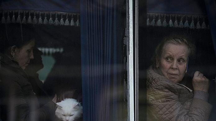 Aus ihrer Heimat vertriebene Menschen warten in einem Bus darauf, dass ukrainische Polizisten ihre Papiere und Habseligkeiten kontrollieren.