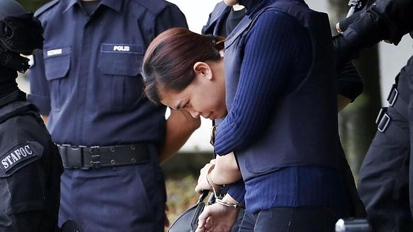 Die angeklagte Indonesierin (mit gesenktem Kopf) wird von Polizeibeamten aus einem Gerichtsgebäude in Sepang geführt.