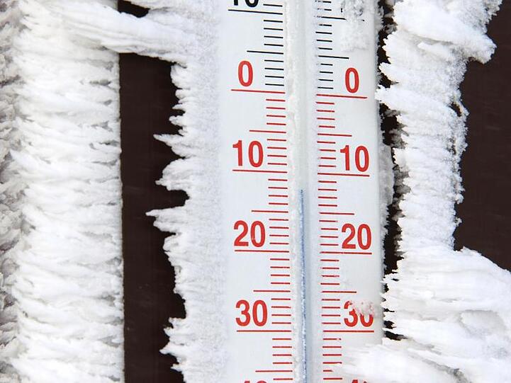 Ein mit Eis bedecktes Thermometer zeigt Minusgrade an. Foto: Matthias Bein/Archiv